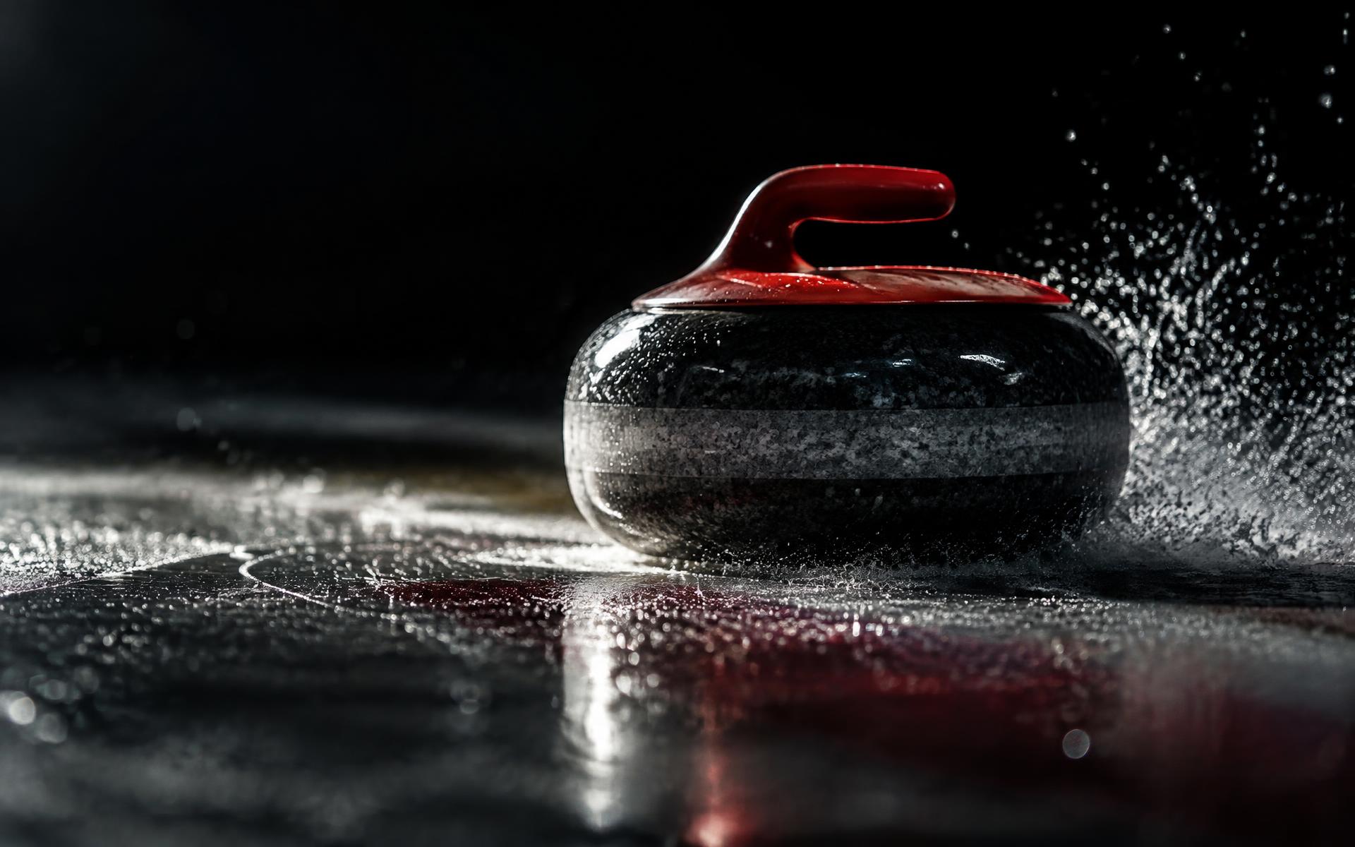 Curling kamen drsi po ledu v zatemnjeni dvorani